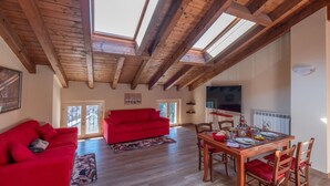 Un vaste espace de vie comprenant un canapé rouge, une table à manger en bois et un téléviseur.