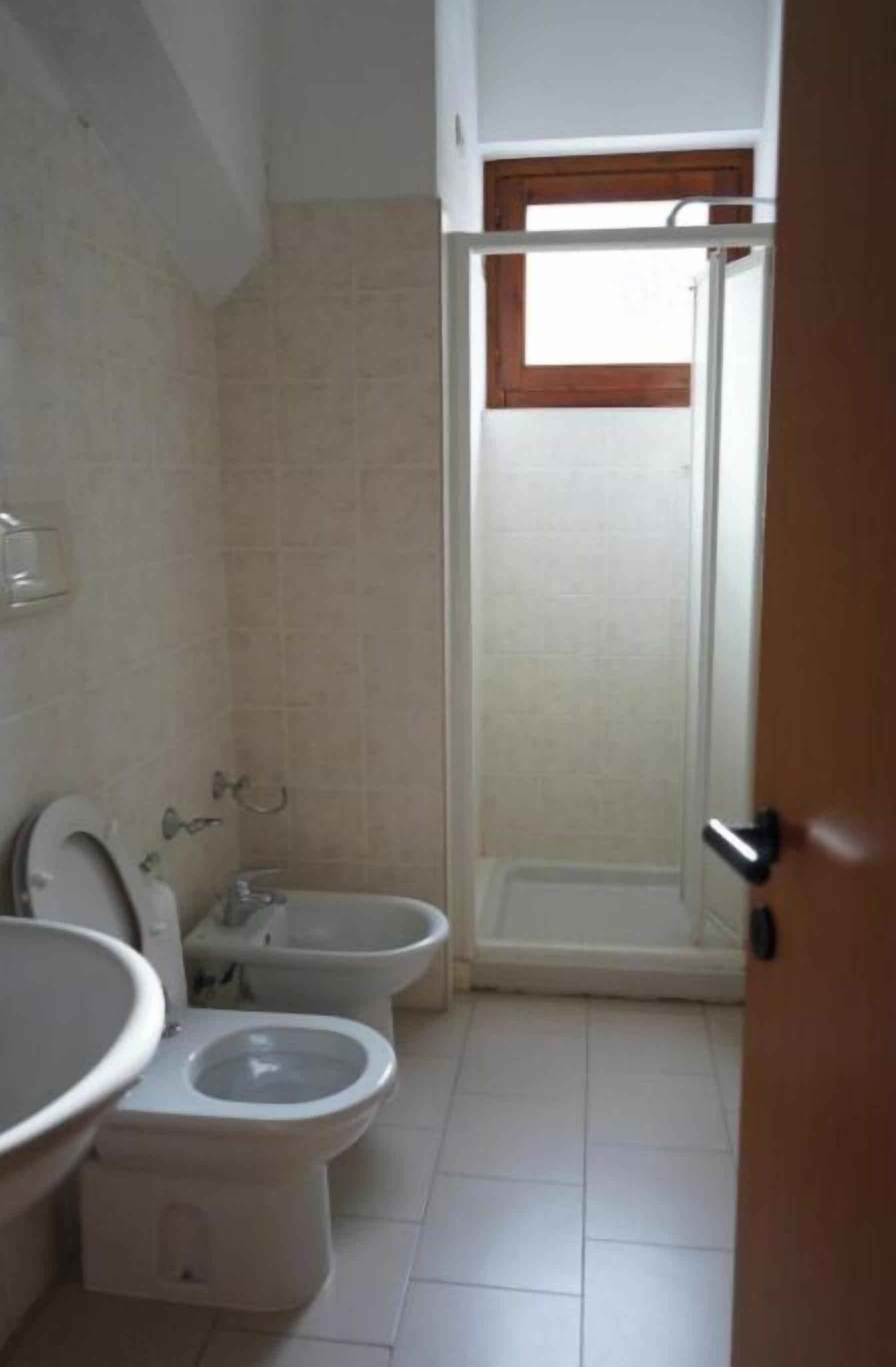 Un baño con dos inodoros, un lavamanos y una ducha.
