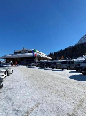 A hotel with a snow-covered parking lot and a mountainous backdrop.