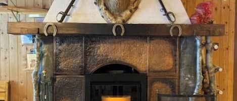A fireplace with a deer head above it, a stone surround, and a tiled floor.