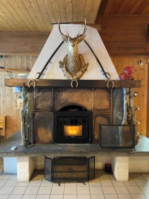 Una chimenea con un venado sobre ella, un marco de piedra y piso de baldosas.