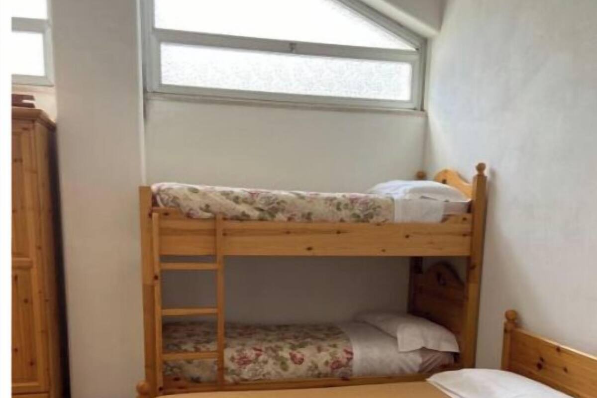 A bunk bed with a wooden frame and a lower bunk with a floral-patterned mattress.