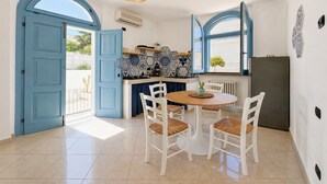 Een keuken met blauwe deuren, een eettafel met stoelen en een hanglamp.