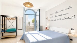 Een slaapkamer met een bed, een hangstoel, een garderobe en een muur met motiverende tekst.