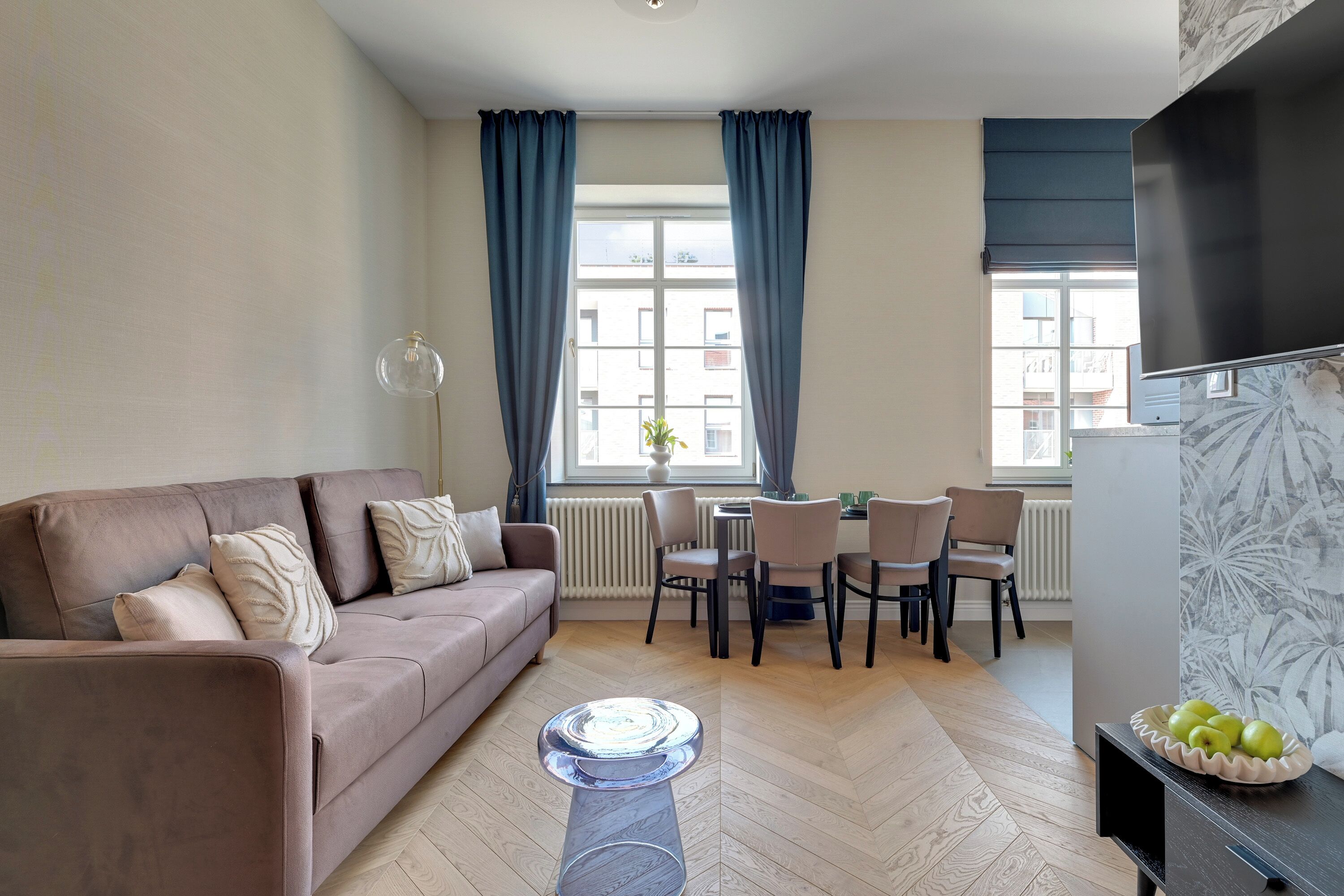 A modern living room with a sofa, dining table, chairs, a coffee table, and a TV.