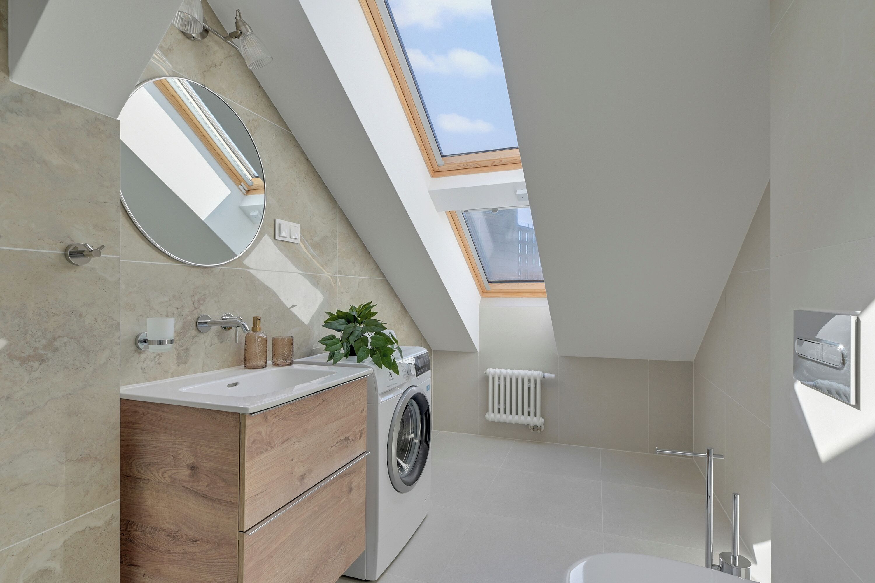 Een moderne badkamer met een dakraam, een wasmachine en een houten wastafelmeubel.
