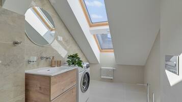 Een moderne badkamer met een dakraam, een wasmachine en een houten wastafelmeubel.
