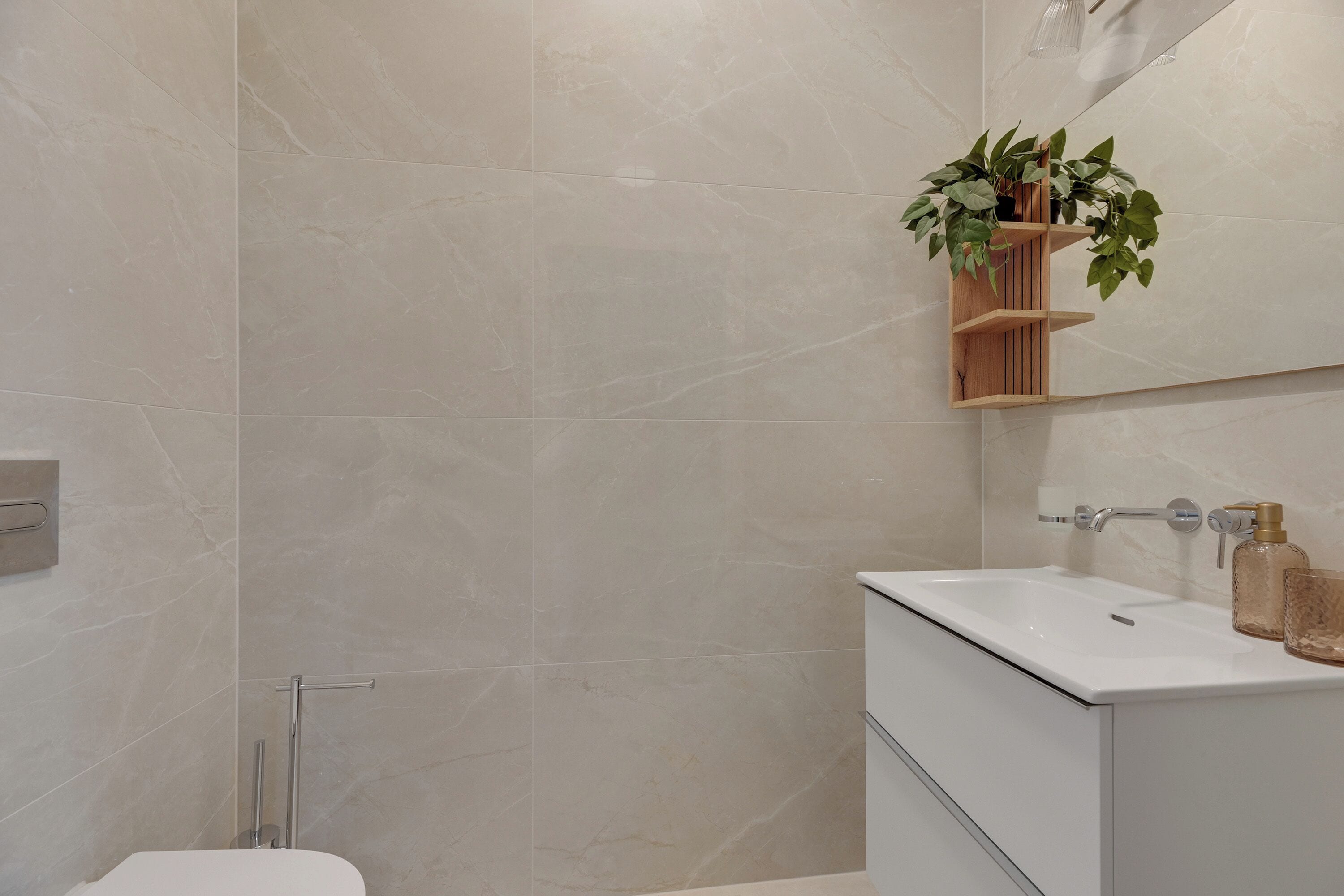 Een moderne badkamer met een wit wastafelmeubel, een spiegel en een houten plank met planten.
