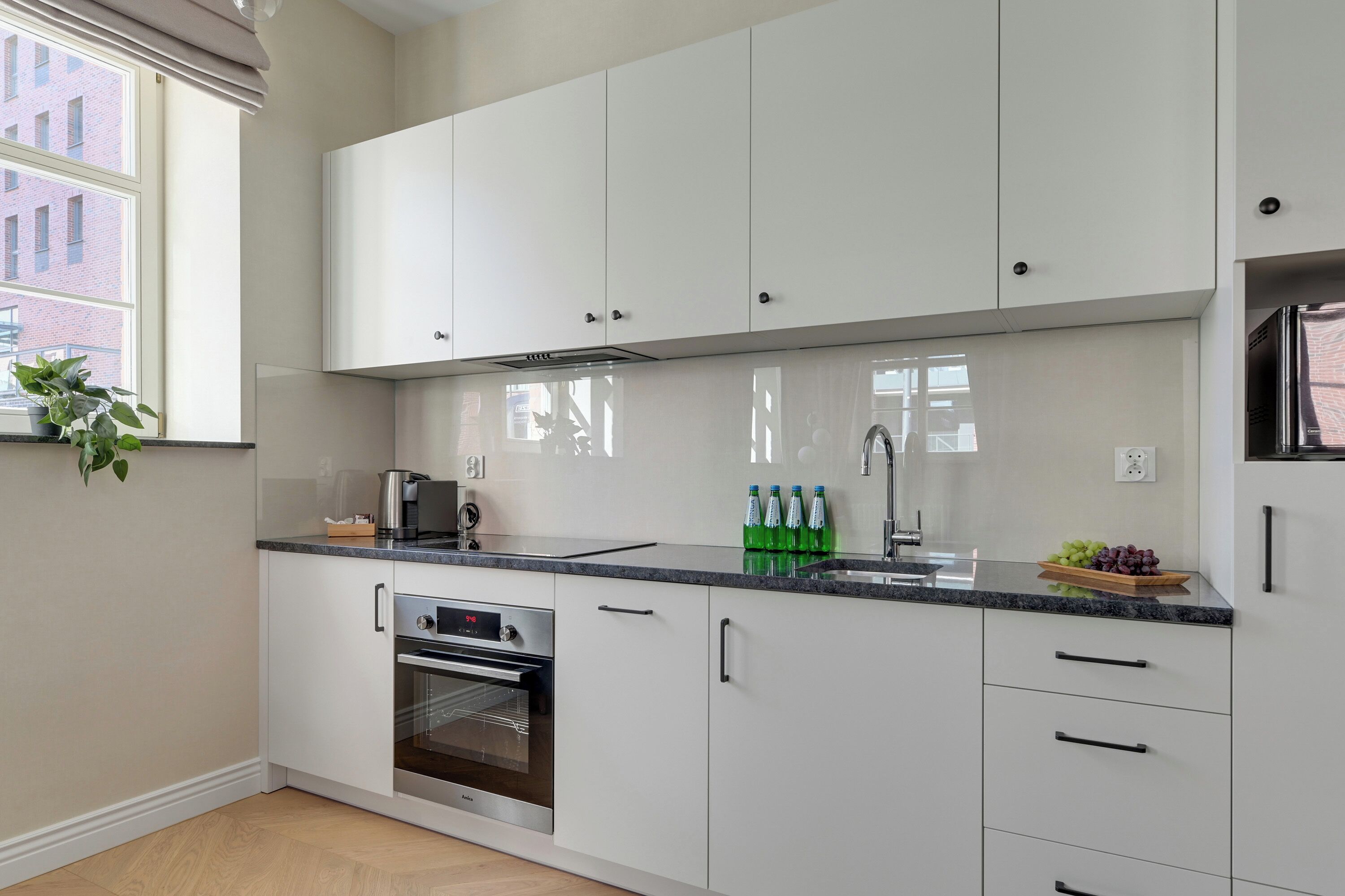 Eine moderne Küche mit weißen Schränken, einem eingebauten Backofen und einem Edelstahlkühlschrank.