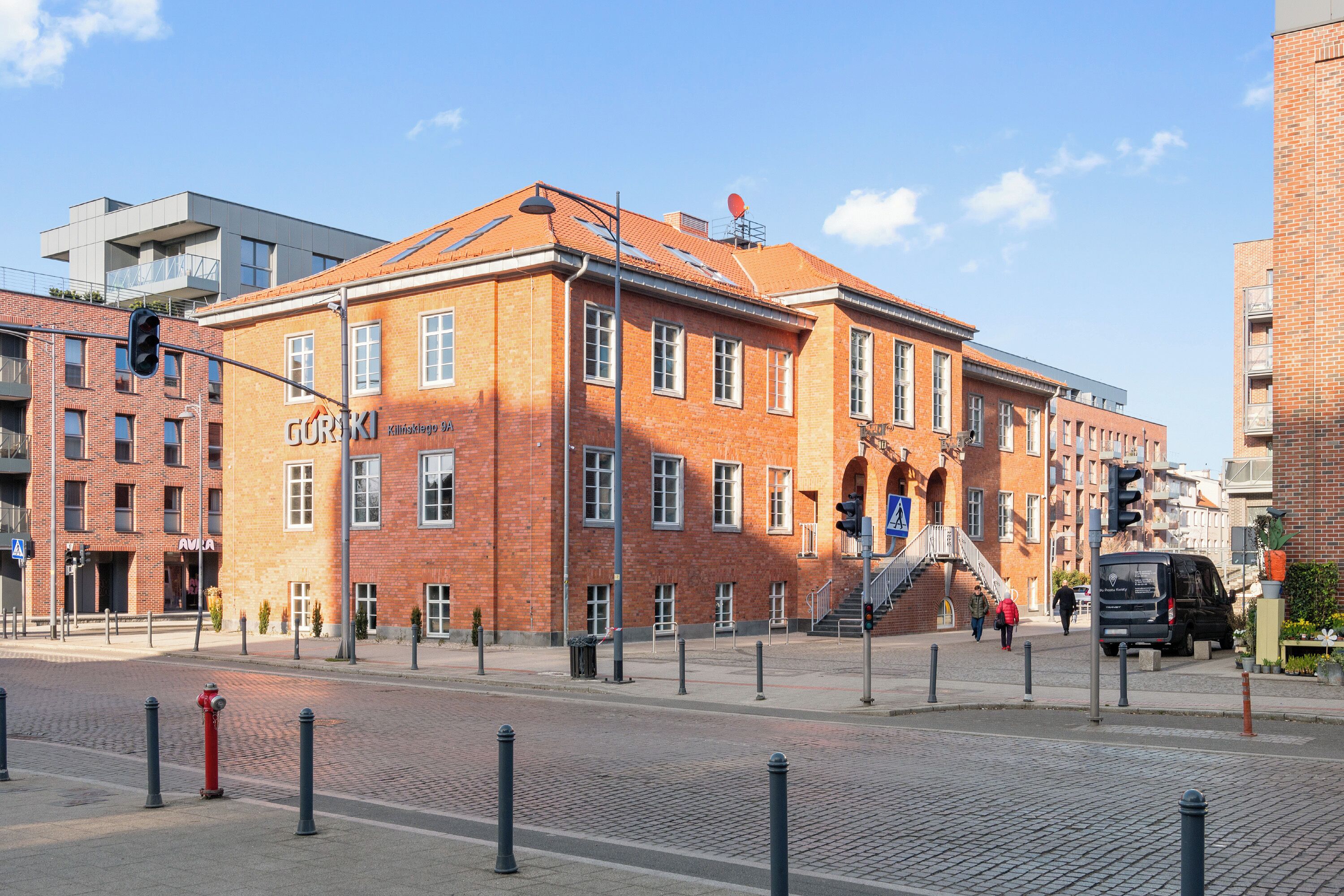 A red brick building with multiple windows and a staircase leading to an upper level.