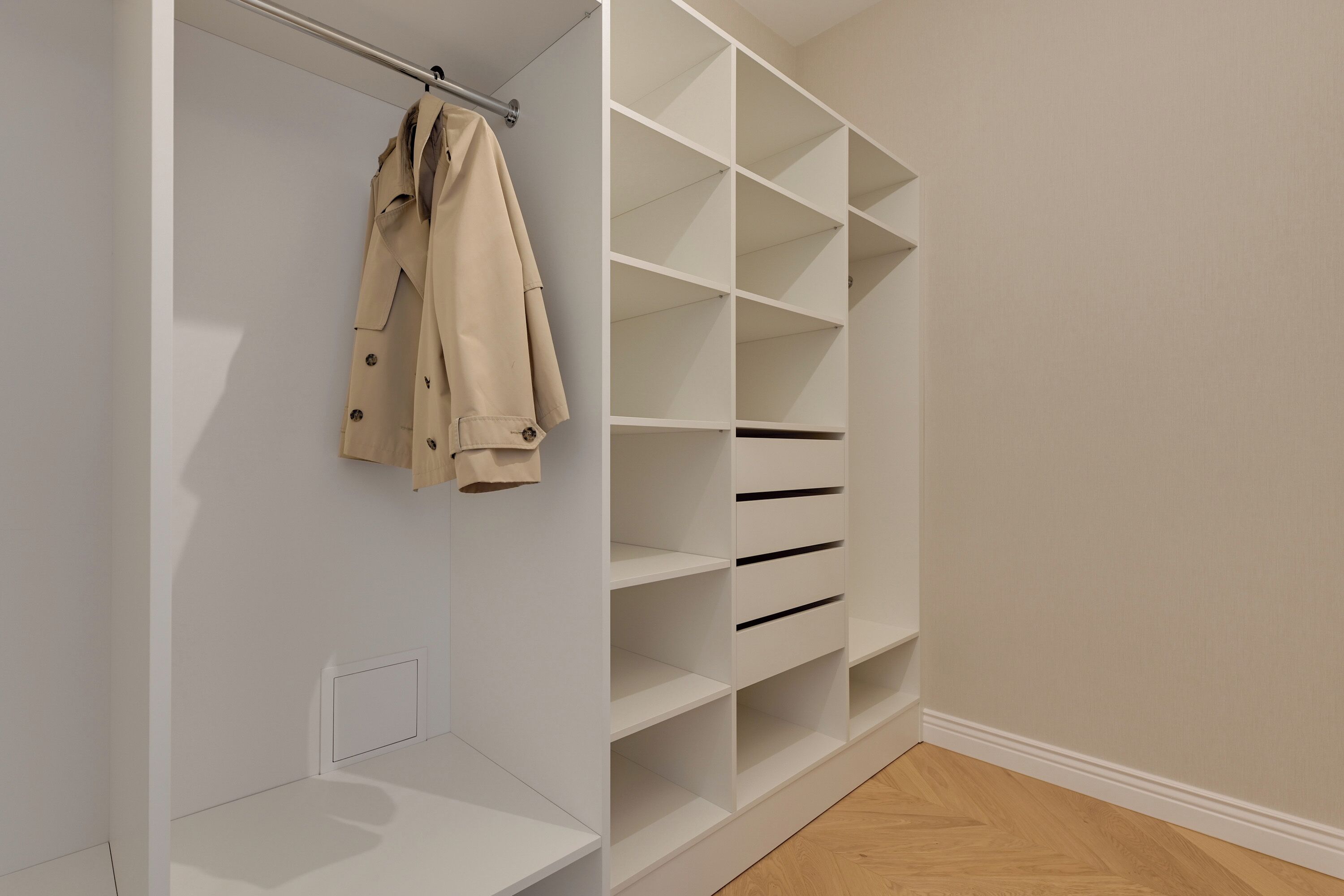 Un dressing sans porte avec des étagères ouvertes, un porte-manteau et un plancher en bois.