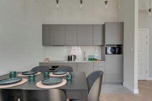 Una cocina moderna con armarios grises, una mesa de comedor con platos y vasos, y un microondas.