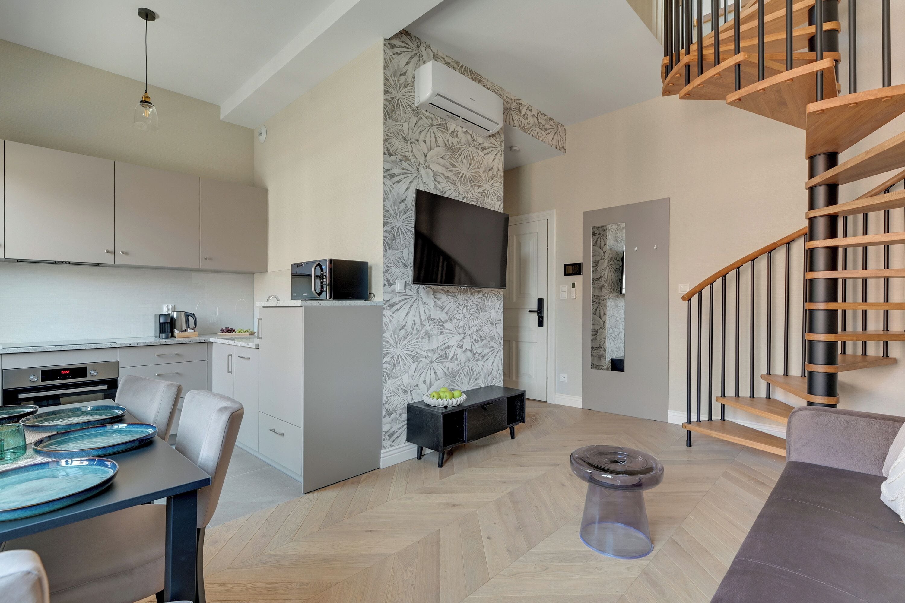 A modern kitchen with a dining area, a staircase, and a living room.