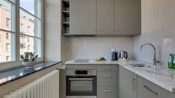 Una cucina moderna con forno integrato, una finestra vista edifici e un piano di lavoro con elettrodomestici.