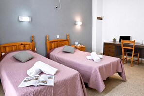 Habitación de hotel con dos camas, un escritorio, una silla y una mesita con una planta.