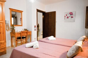 Un dormitorio con dos camas, un escritorio de madera, un espejo y una puerta.