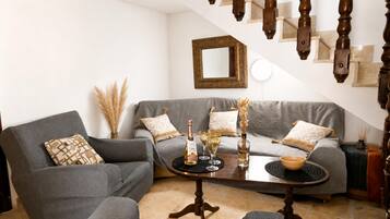 Un salón con un sofá gris, una mesa de centro y una escalera con barandillas de madera.