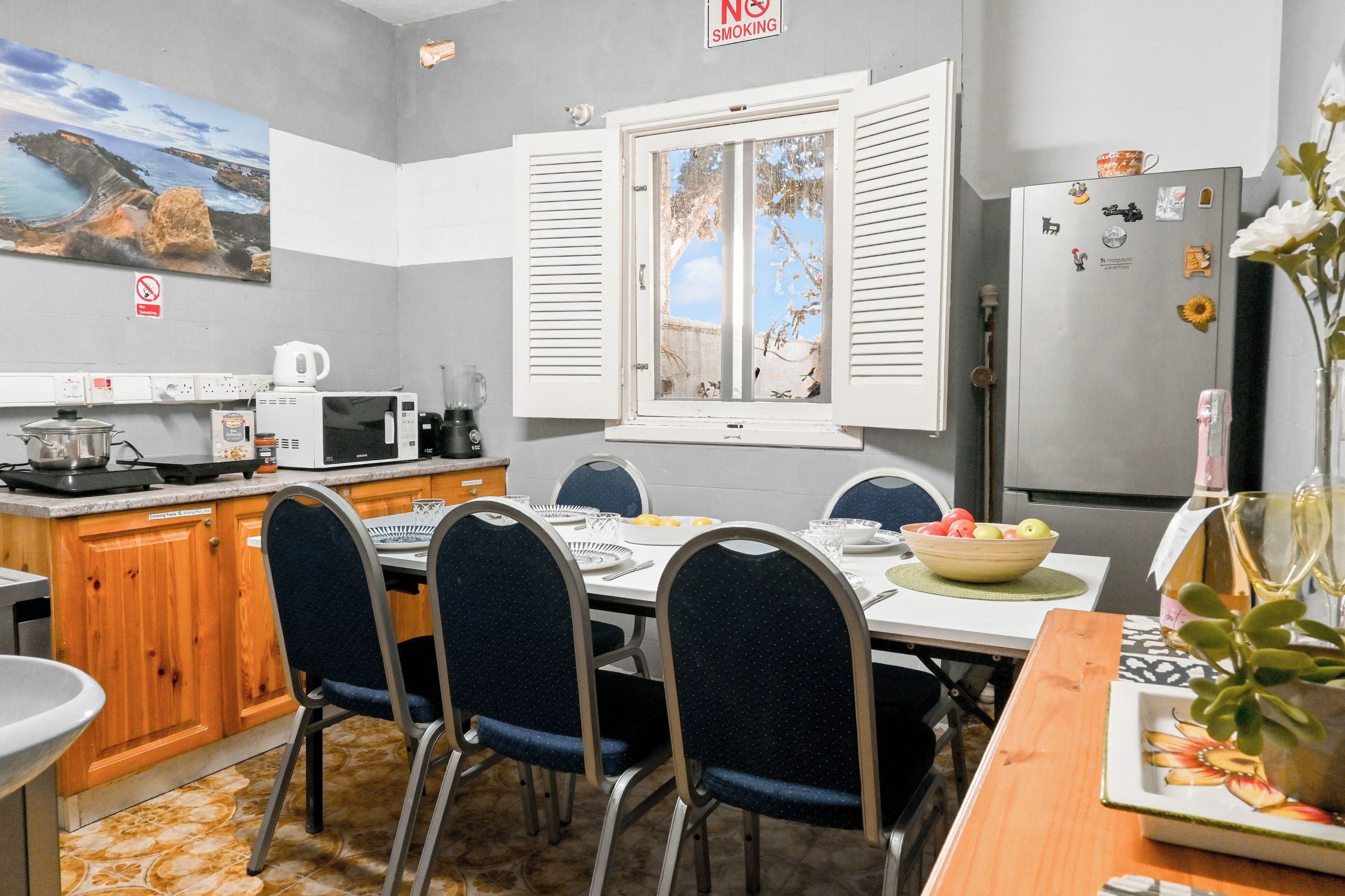 Una cocina con mesa, sillas, refrigerador y microondas.
