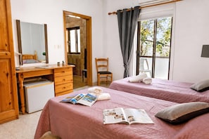 Un dormitorio con dos camas, un escritorio, una silla y una ventana con cortinas.