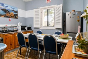 A kitchen with a dining table, chairs, a refrigerator, and a microwave. - Sefranda Guesthouse Ensuite Rooms (St. Julian's)