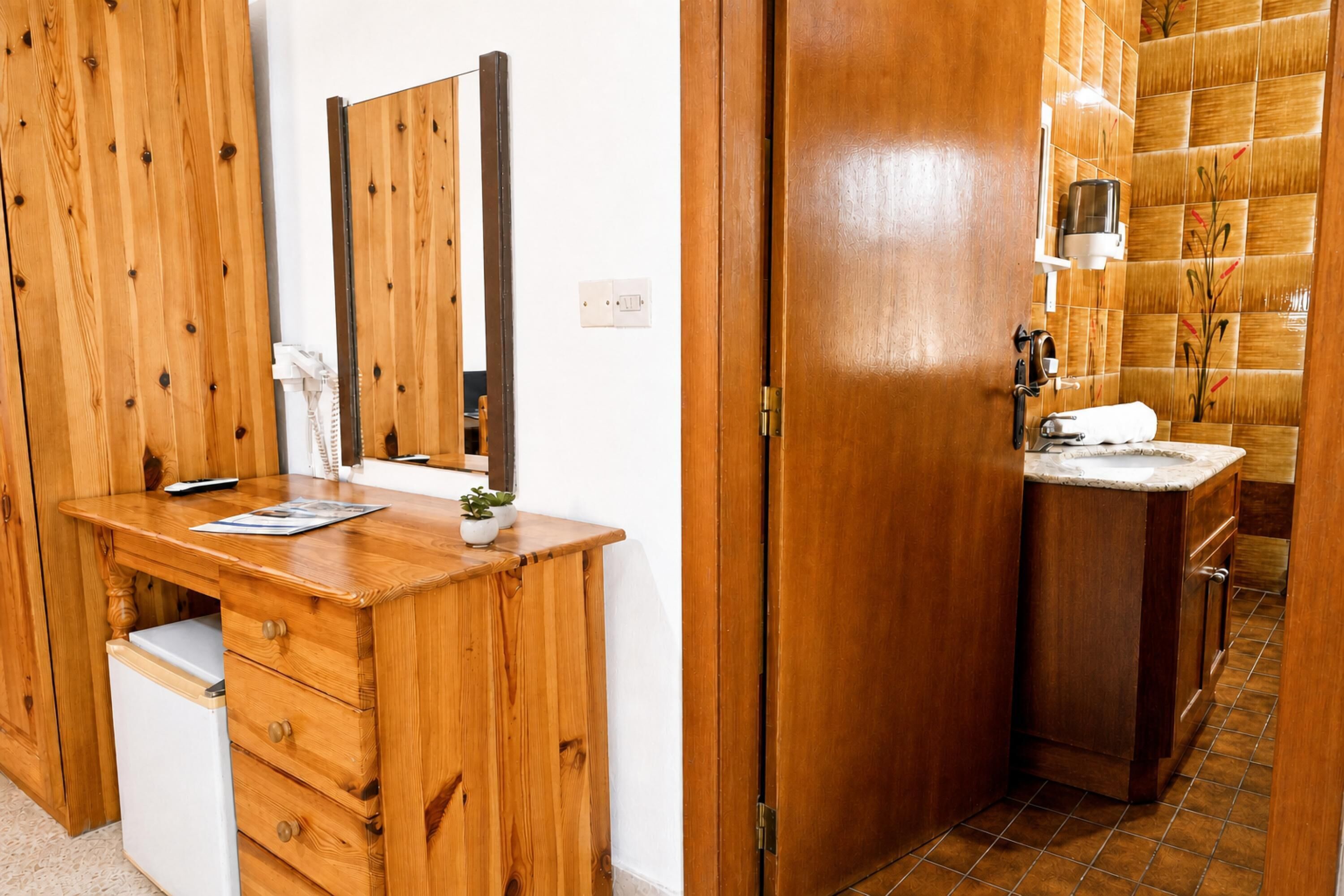 Ein Holztisch mit Spiegel, einer kleinen Pflanze und einem weißen Schubladenschrank.
