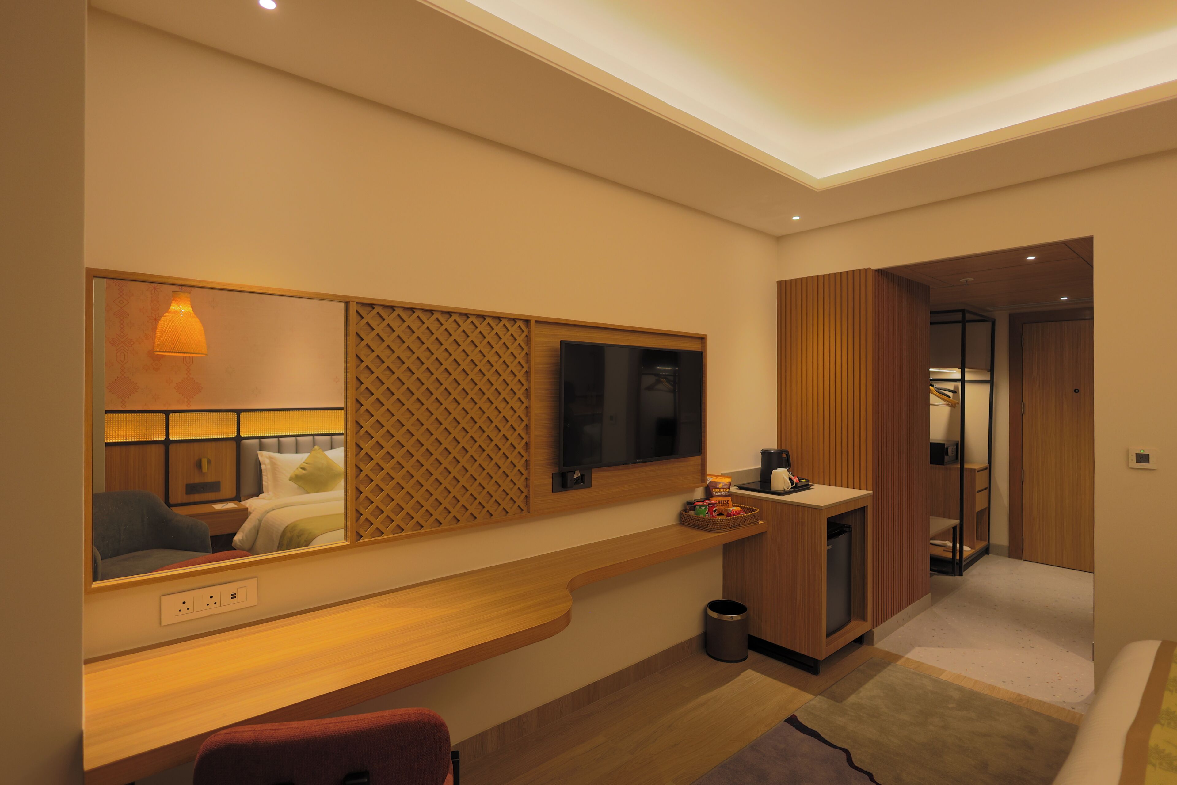 Una habitación de hotel moderna con un espejo grande, una consola de madera y un escritorio pequeño.