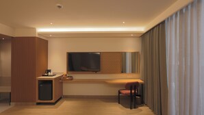 A hotel room with a wooden desk, a television, a chair, and a small refrigerator. - Hotel Palacio Paltan Bazaar (Guwahati)