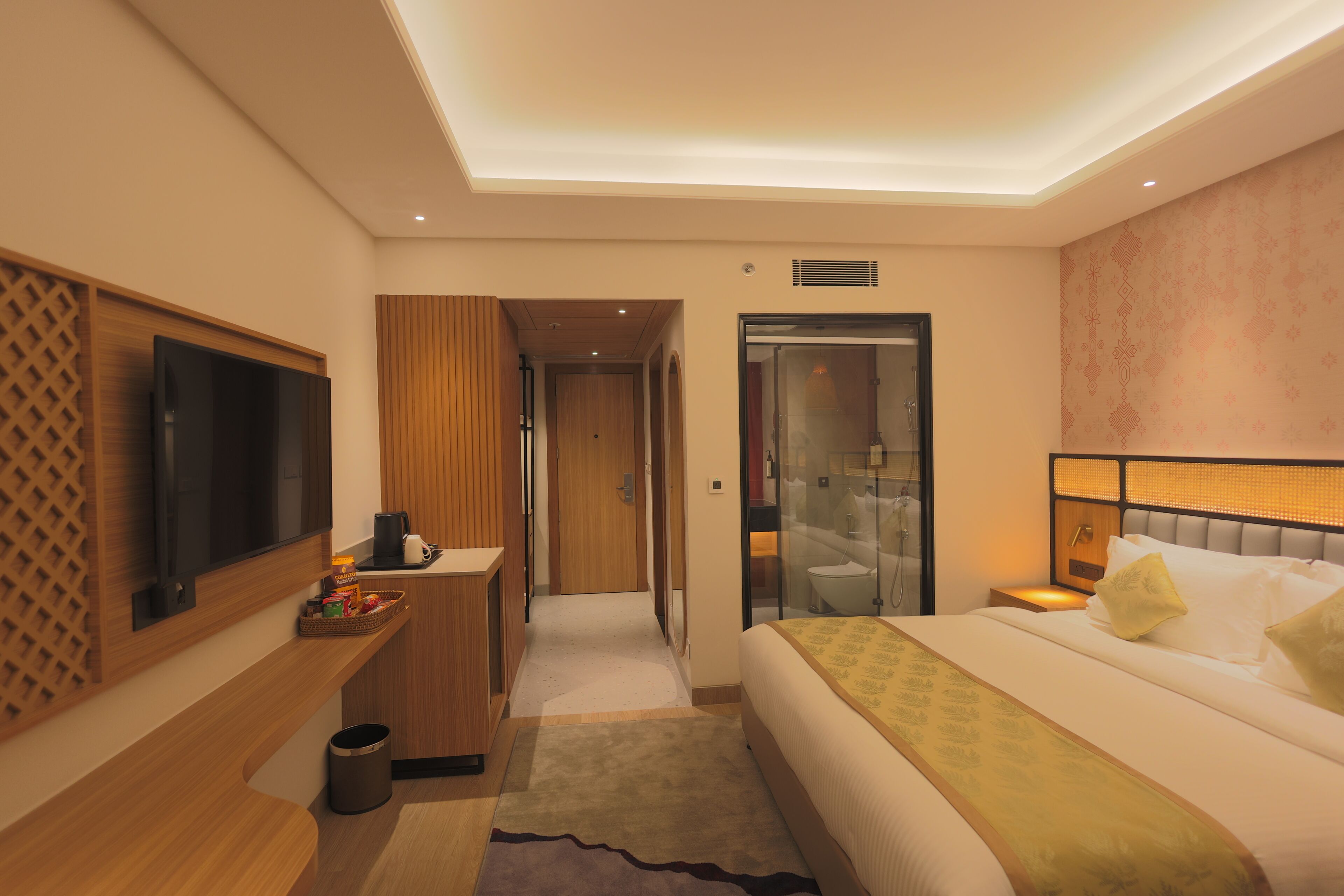 A hotel room with a bed, a TV, a desk, a bathroom, and a shower.
