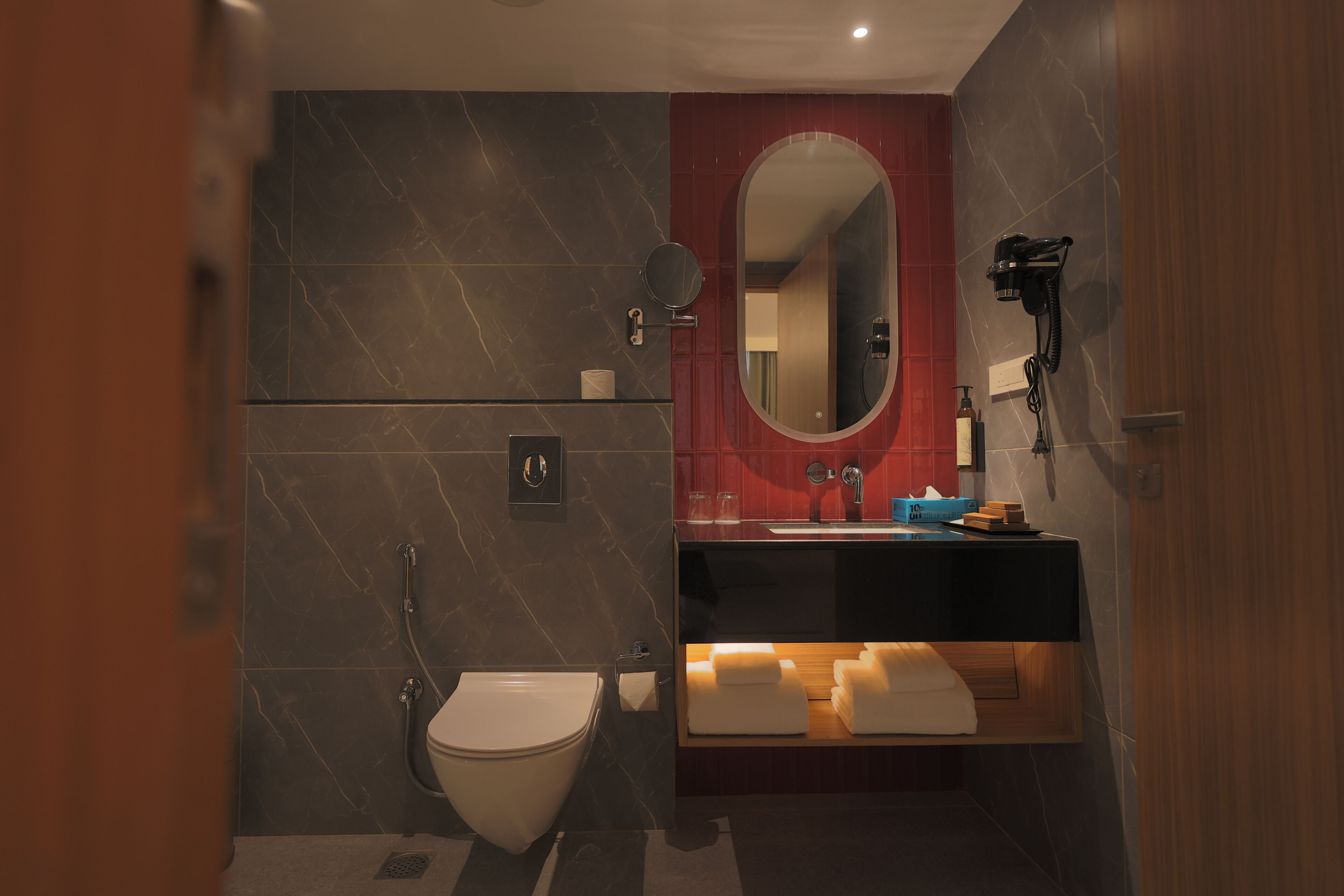 A modern bathroom with a toilet, sink, mirror, and towel rack.