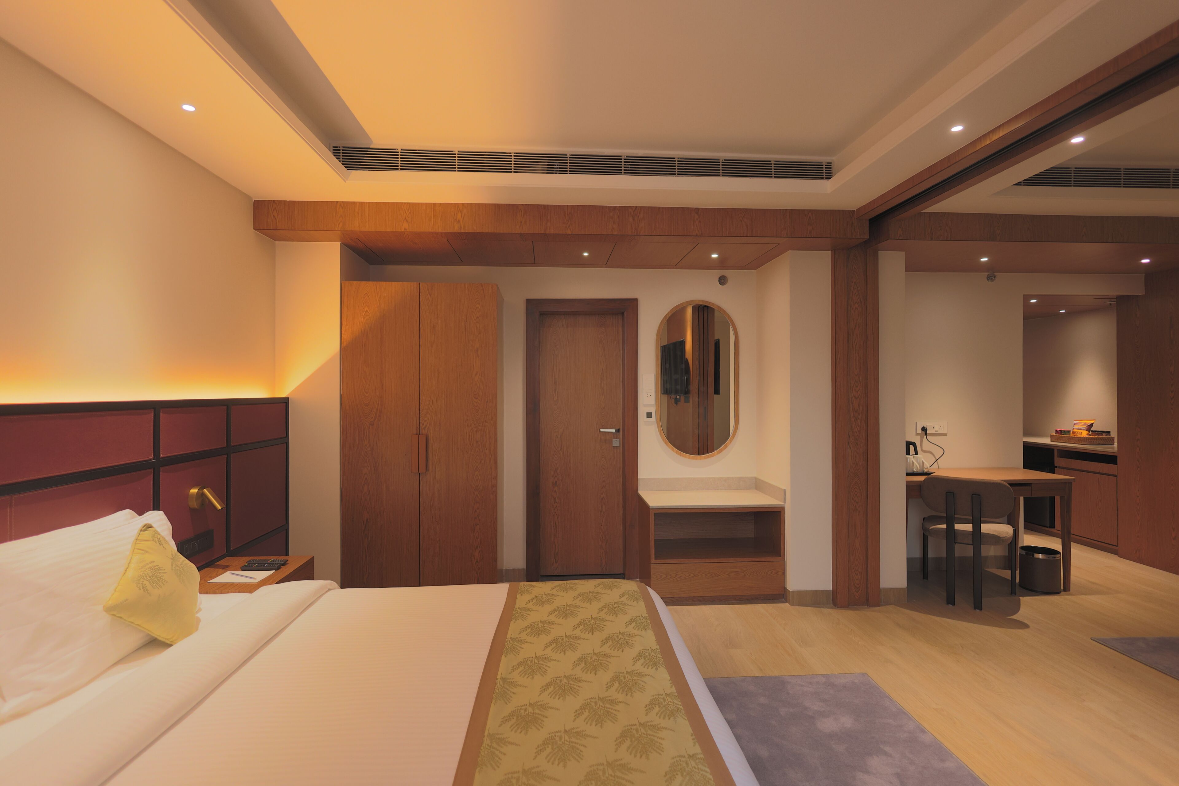 A hotel room with a bed, a desk, a mirror, and a bathroom.