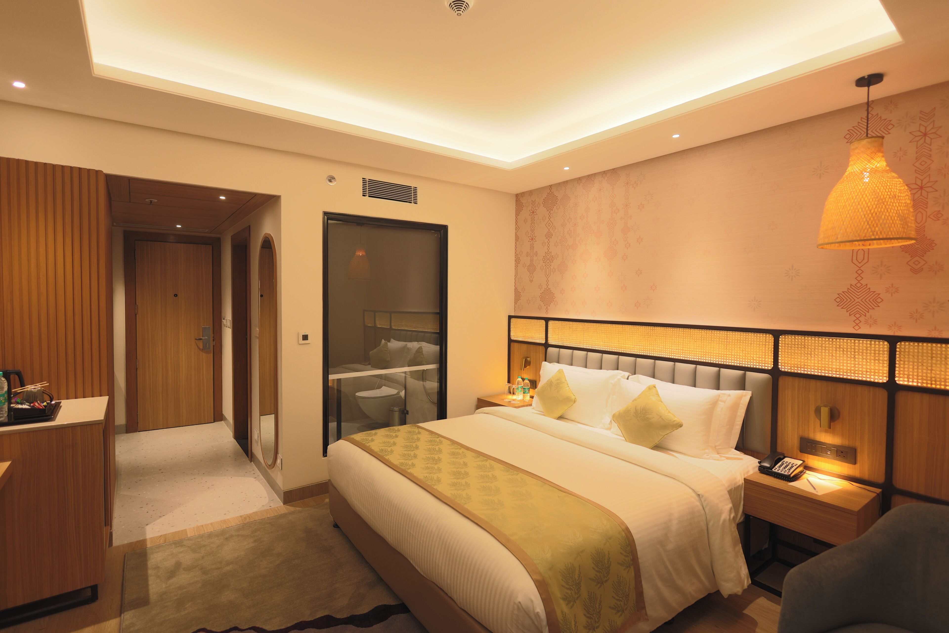 A hotel room with a bed, bedside table, lamp, and a wardrobe.