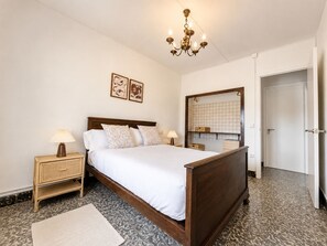 Un dormitorio con una cama de madera, mesitas de noche con lámparas, un espejo y un suelo con diseño.