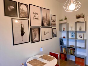 A room with a round table, bookshelves, and framed pictures on the wall. - "Mylo's Home" Boutique apartment at 20 min. Duomo, Prada Foundation, IEO (Milano)