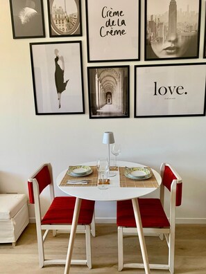 A dining area with a round table, two chairs, and framed artwork on the wall. - "Mylo's Home" Boutique apartment at 20 min. Duomo, Prada Foundation, IEO (Milano)