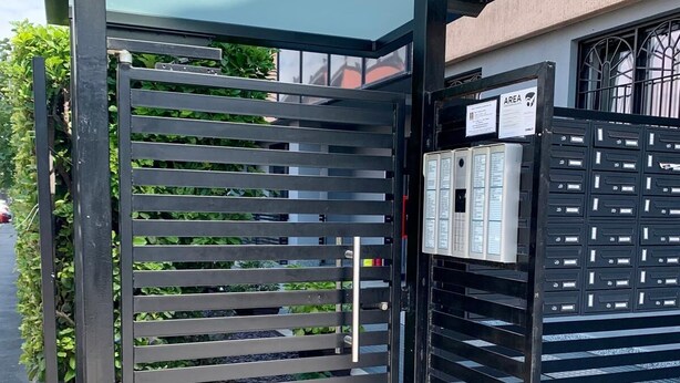 Une entrée fermée par un portail en métal et une boîte aux lettres fixée au mur.