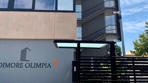 Un bâtiment moderne, sur lequel on peut lire l’inscription « Dimore Olimpia 7 », et une clôture en métal.
