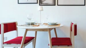 Un coin repas avec une table ronde, deux chaises et des œuvres d’art encadrées accrochées au mur.