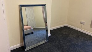 Une pièce dotée d’un grand miroir, d’une porte et d’un sol recouvert de moquette.