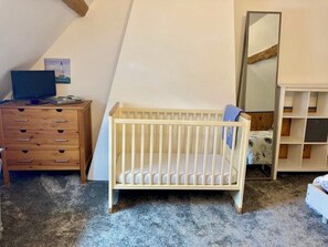 Een kamer met een houten ledikant, een kapstok, een spiegel en een boekenkast.