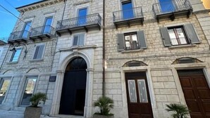 Un bâtiment historique en pierre, doté de nombreux balcons, d’une entrée centrale et de plantes en pot.