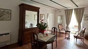 Un coin repas avec une table ronde, des chaises, un buffet et une plante en pot.