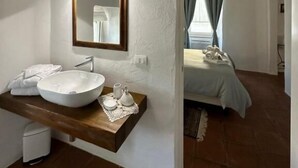 Une salle de bain avec un lavabo blanc, un miroir et un plan de toilette en bois.