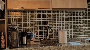 A kitchen with wooden cabinets, a granite countertop, a coffee maker, and a kettle. - Cozy house in Angra dos Reis (Angra dos Reis)