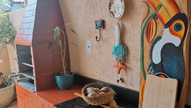 A kitchen with a brick oven, a blue potted plant, a woven basket with eggs, and a decorative wall piece. - Cozy house in Angra dos Reis (Angra dos Reis)
