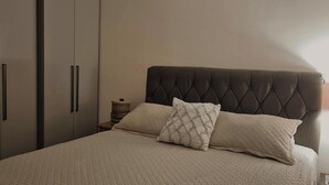 A bedroom with a bed, two pillows, a headboard, a nightstand, and a wardrobe. - Cozy house in Angra dos Reis (Angra dos Reis)