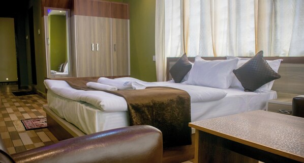 Une chambre d’hôtel comprenant un lit, un bureau, une chaise, une armoire et un miroir.