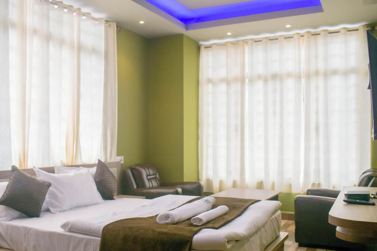A hotel room with a bed, a chair, a table, and curtains.