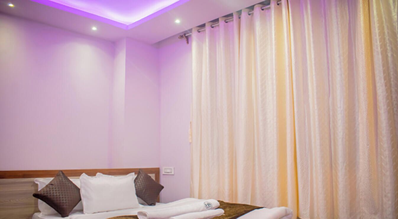 A bedroom with a bed, pillows, and a curtain.