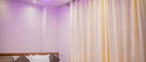 A bedroom with a bed, pillows, and a curtain.
