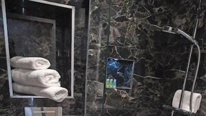 A modern bathroom with a marble wall, a toilet, a glass-enclosed shower, and a towel rack. - Moy Hotel (Foxford)